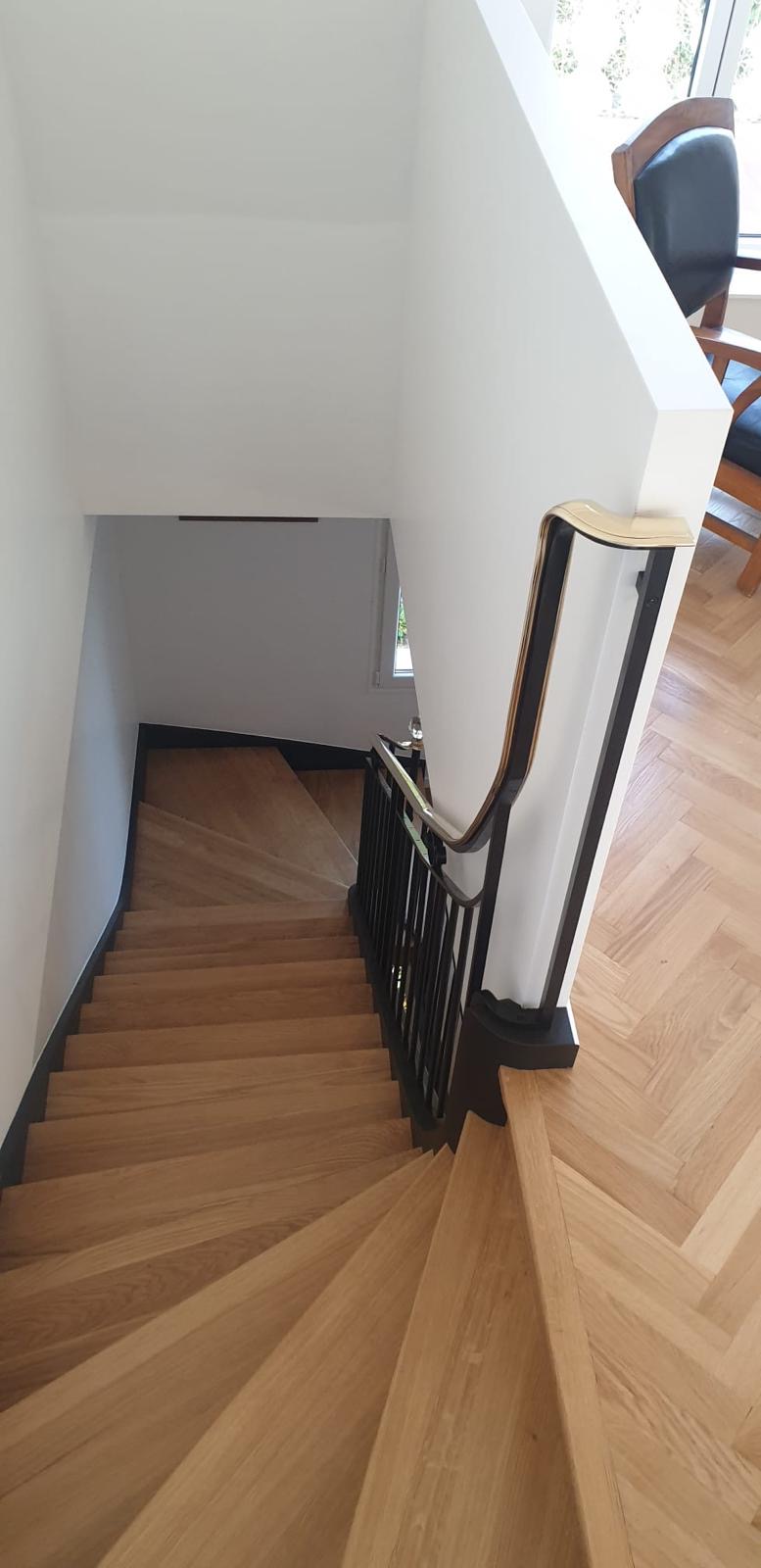Vue de l’escalier depuis le palier : marches en bois et main courante dorée