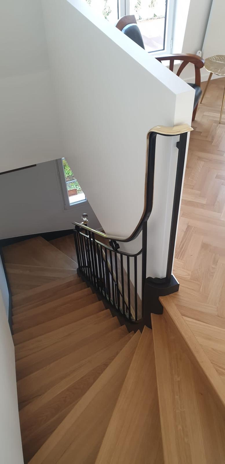 Escalier en bois avec rampe noire et main courante dorée